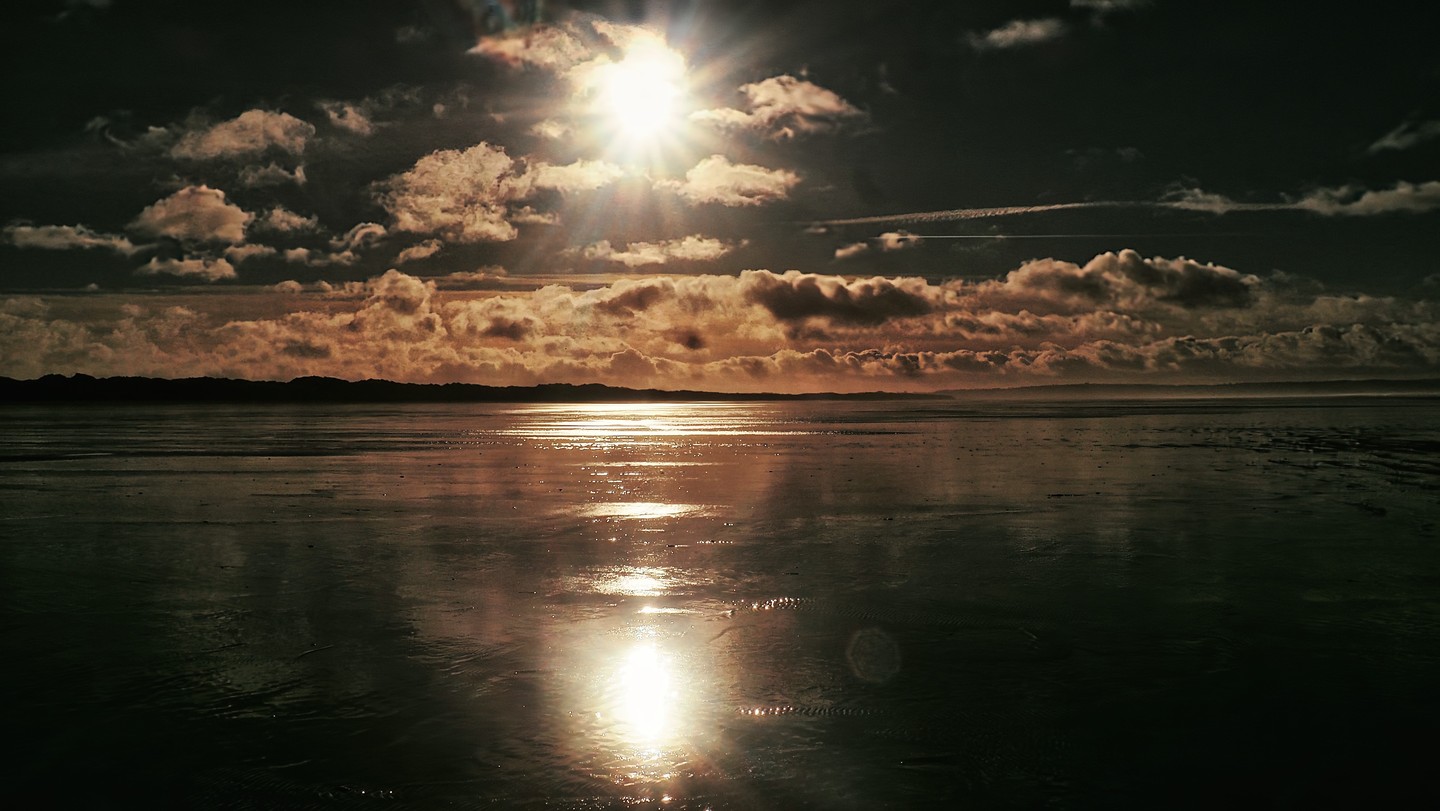 Sun Bursting Through Dark Dramatic Clouds Tidal Flat Wet Sand Reflection